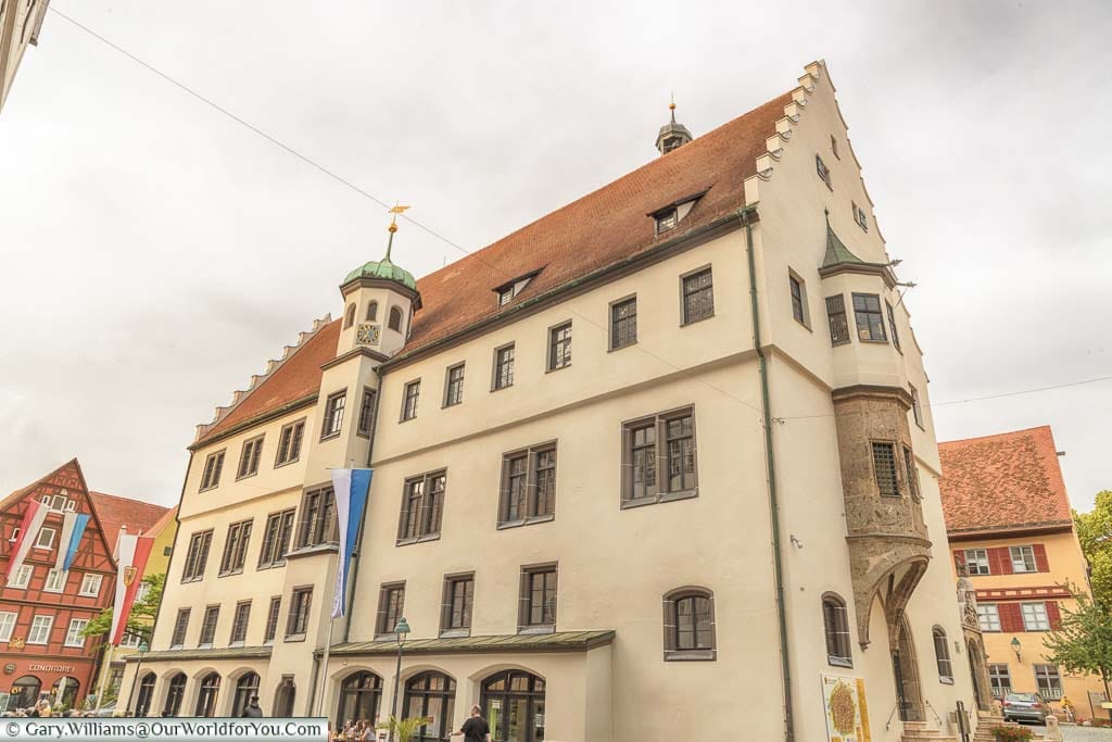 The historic Rathaus of Nördlingen in a sandy colour with an orange tiled roof.