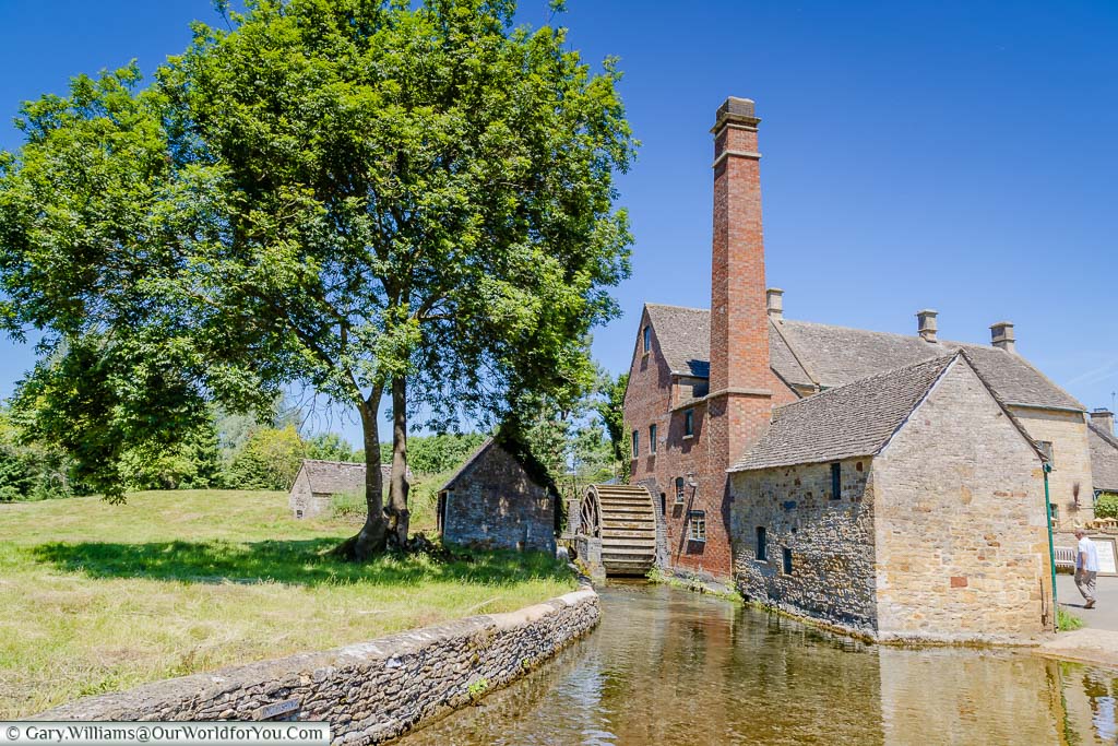 An idyllic Cotswold scene of the watermill in Lower Slaughter under a deep blue sky
