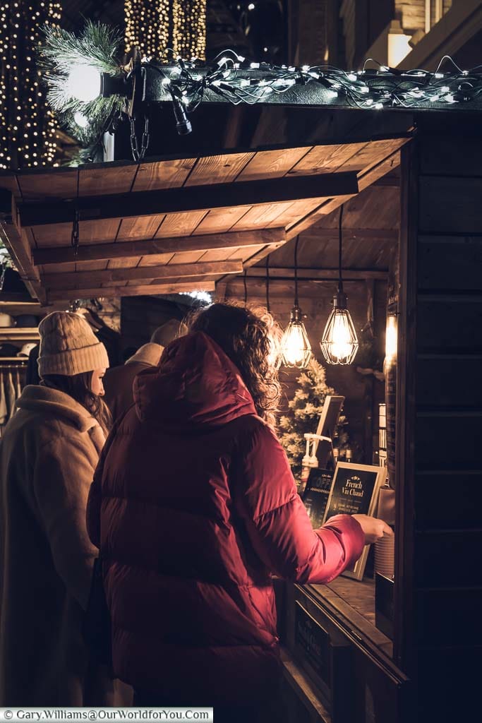 A group of ladies buying mulled wine from a wooden stall in Hay’s Galleria