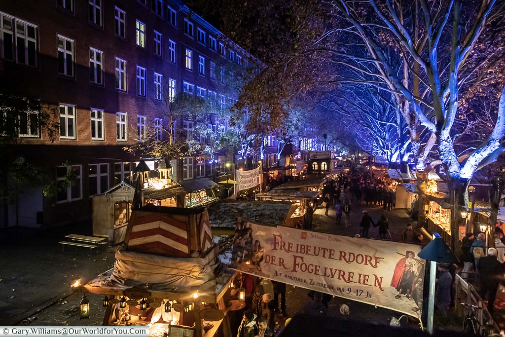 Looking down on the Bremens River Christmas markets under a canopy of trees lit in electric blue.