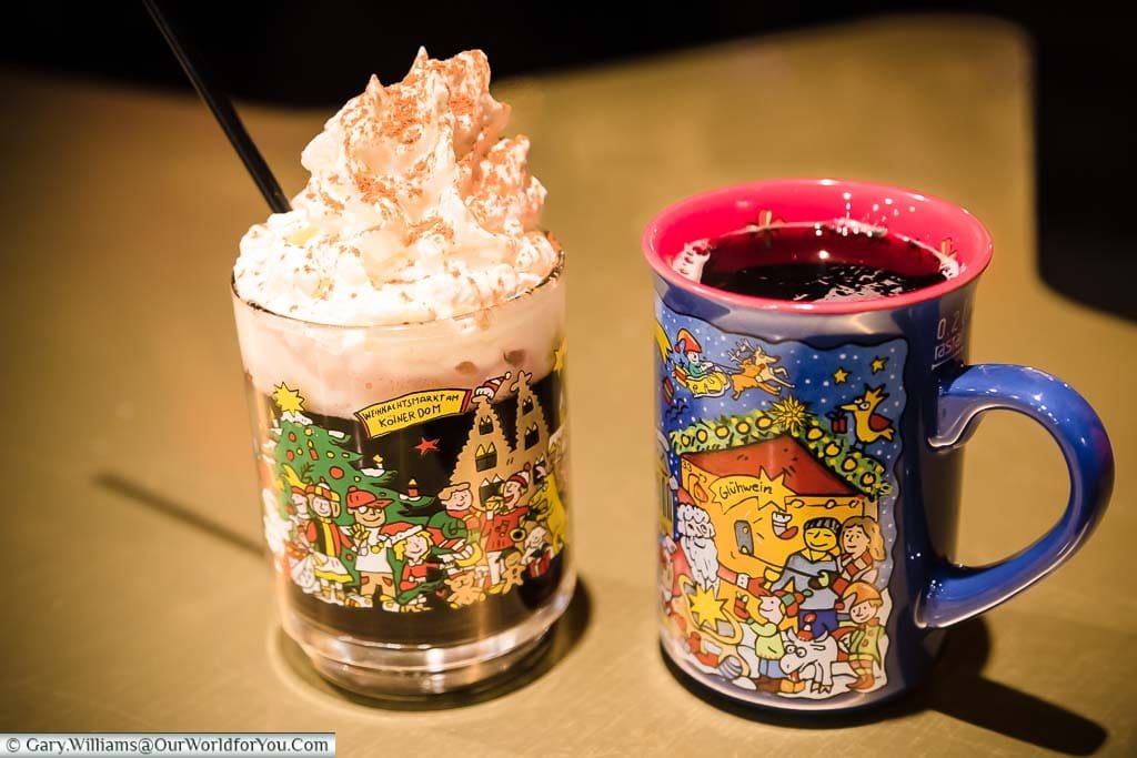 Glühwein in a bright seasonal mug & and Alpenpower in a glass mug at the Dom Christmas Market in Cologne