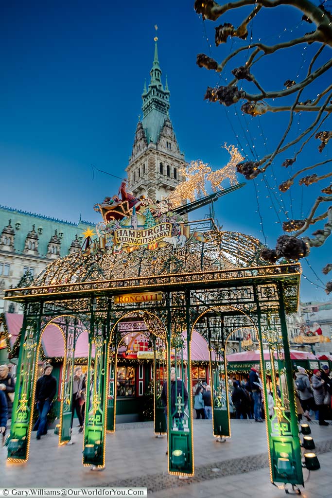 The decorative illuminated entrance gates to Hamburg's Weihnachtsmarkt Christmas market with the Rathaus tower in the background.