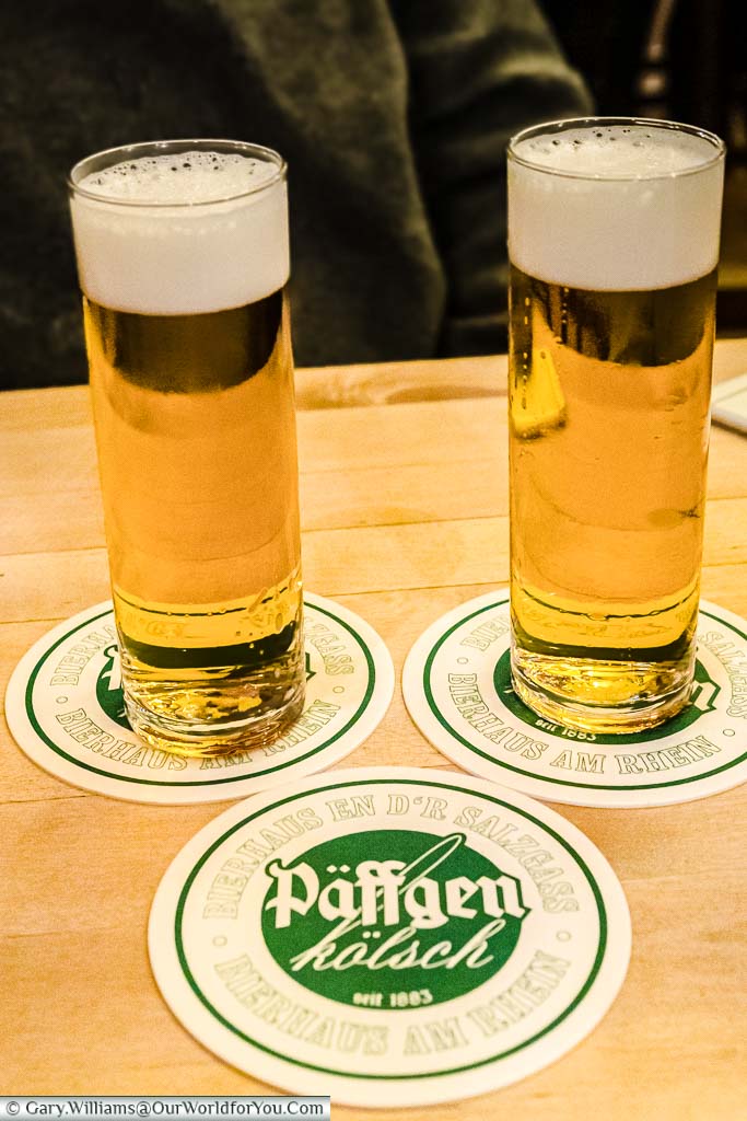 Two crisp glasses of Kolsch on top of their beer mats with a third used to keep a tally of the total consumed.