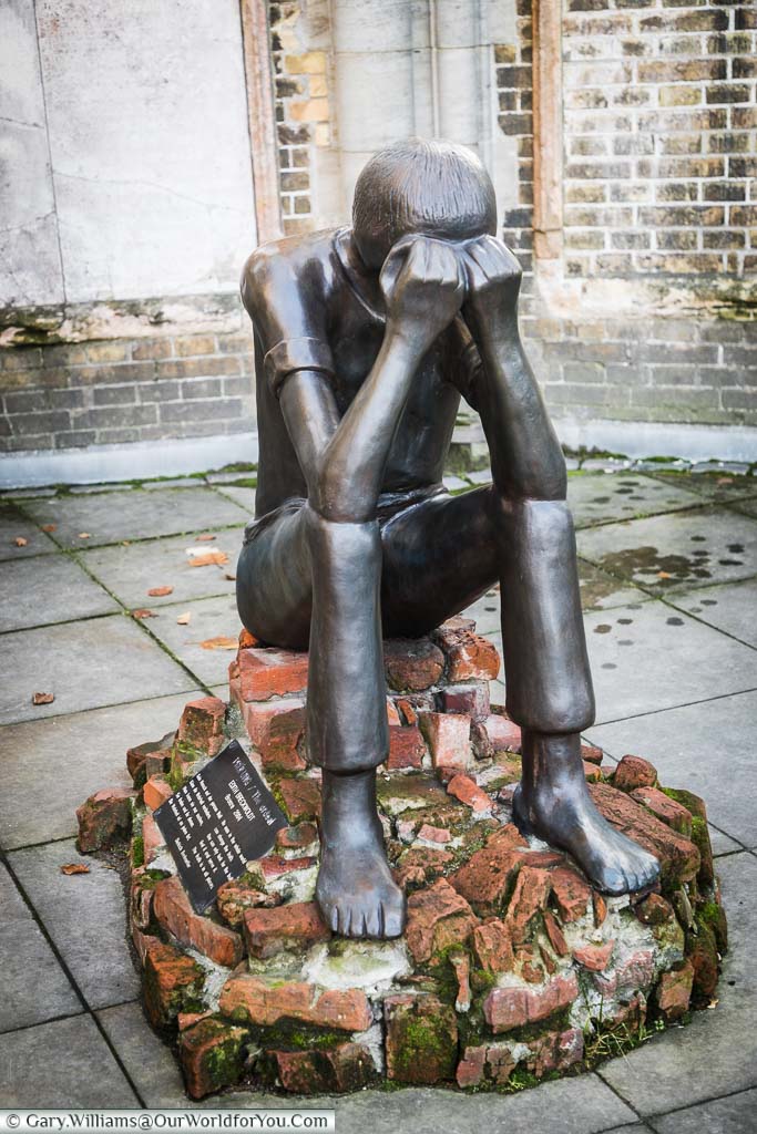 The Ordeal, by Edith Breckwoldt. A bronze statue of a barefooted man sitting on a pile of bricks with his head in his hands.