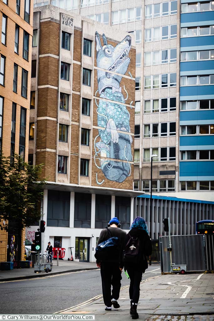 A mural of a strange-looking clothed dog/wolf on the side of an office block in Bristol