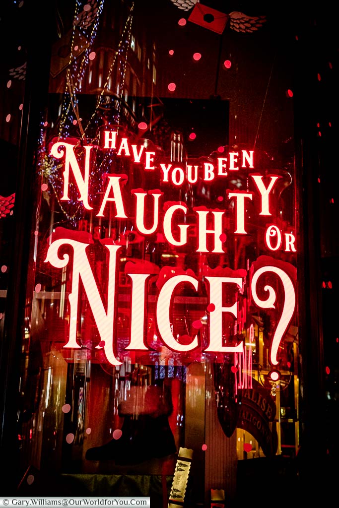 A red neon sign in a shop window on Regent Street asking "Have you been Naughy or Nice?"
