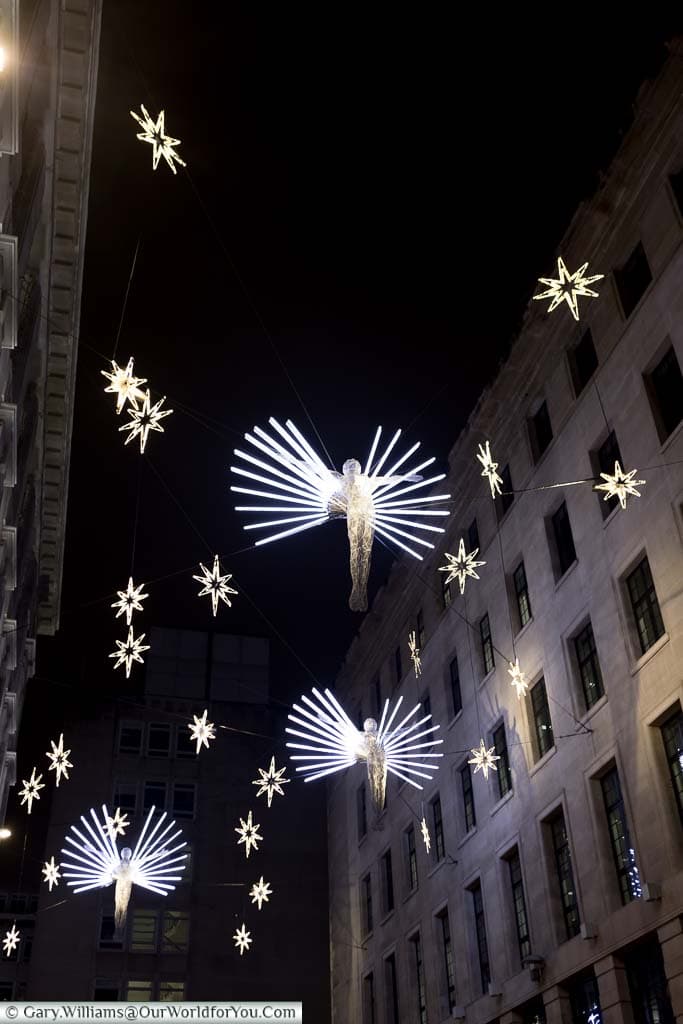 Floating illuminated angels hanging over Charles II Street in the West End of London at Christmas
