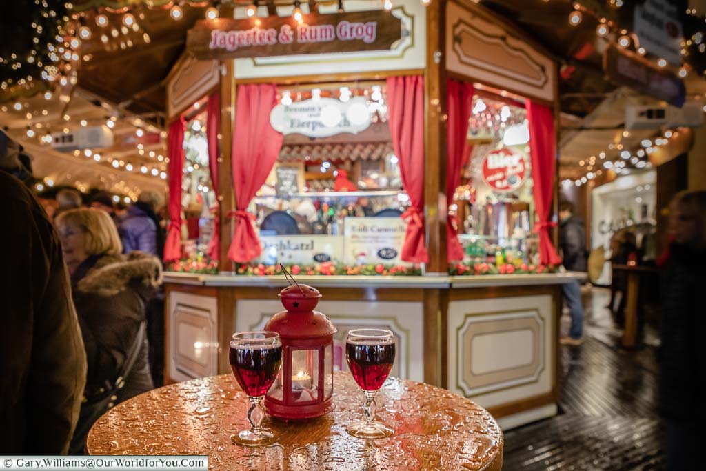 Two wine glasses full of glühwein on a wet table in front of a drinks cabin in the Christmas markets of Bremen, Germany
