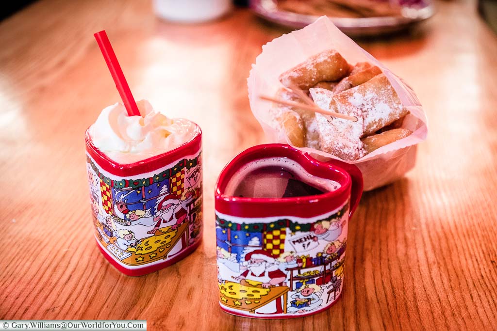 Heart-shaped Christmas mugs and a bag of little mini doughnut style treats dusted with icing sugar on a bench in Bremen's Christmas Markets.