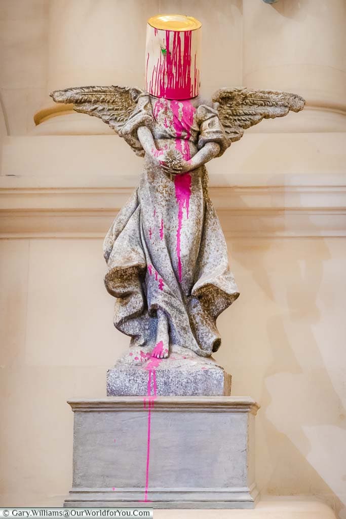 The Banksy artwork 'Paint Pot Angel' depicting a stone angel with a pot of pink paint deposited over the head now in the Bristol Museum & Art Gallery