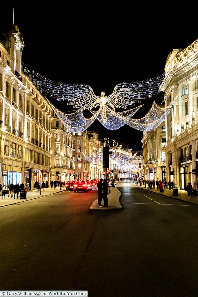 A view along Regent street with its illuminated Christmas Angels outstretched between either sides of the wide shopping street.
