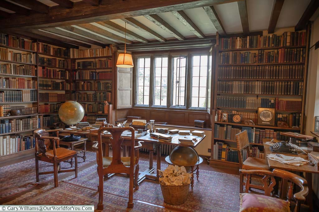 Rudyard Kipling's desk in front of the window of the book-lined shelved walls of the study at Bateman’s