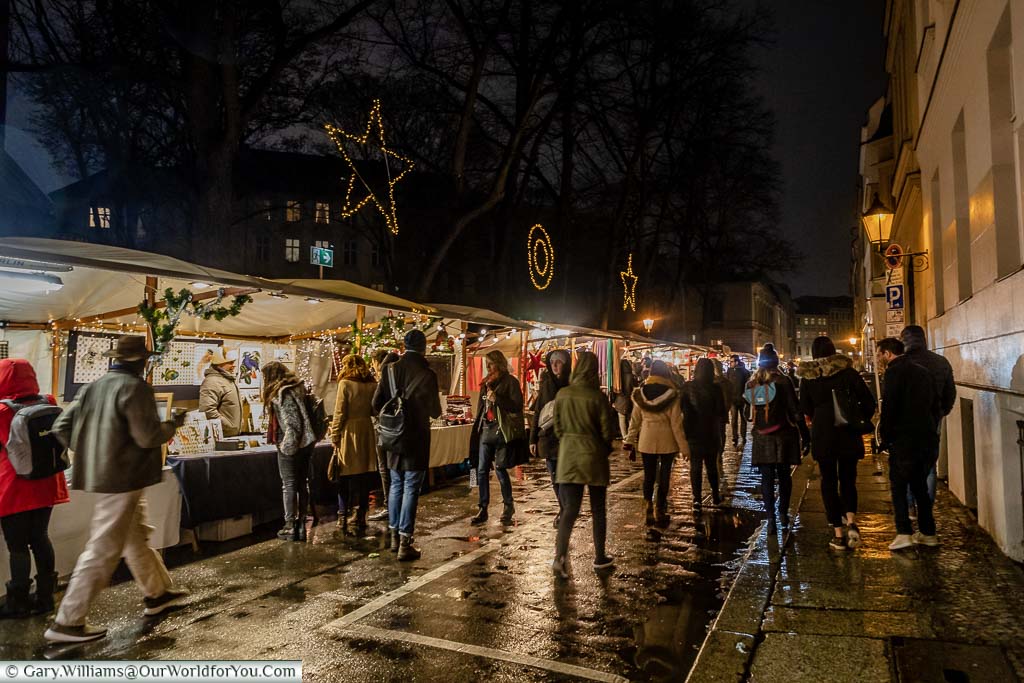 Shoppers walking along the Sophienstrasse Christmas Market on a damp evening in Berlin, German