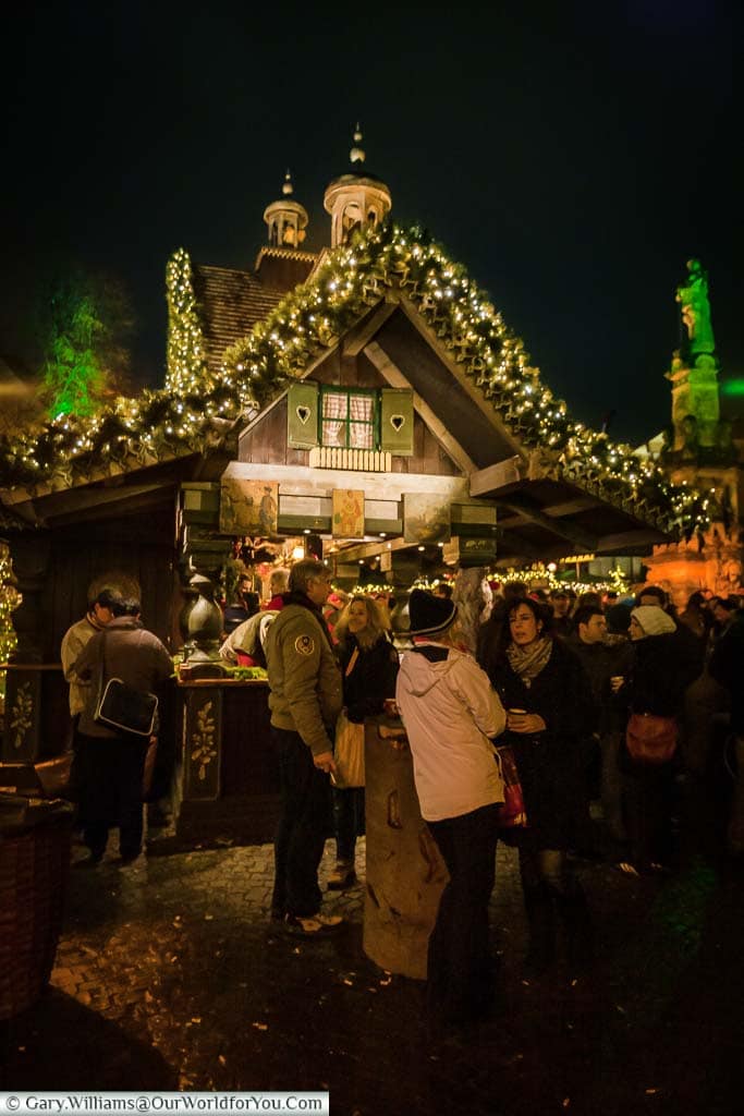 Crowds in front of a drinks hut in the Cologne Christmas Markets after dark.