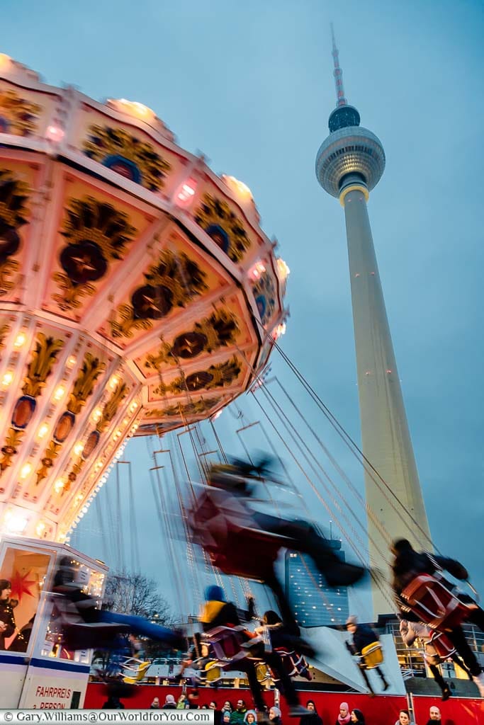 The swing carousel at the Berliner Weihnachtszeit Christmas Market with the Berliner Fernsehturm, or Berlin Tower, in the background.