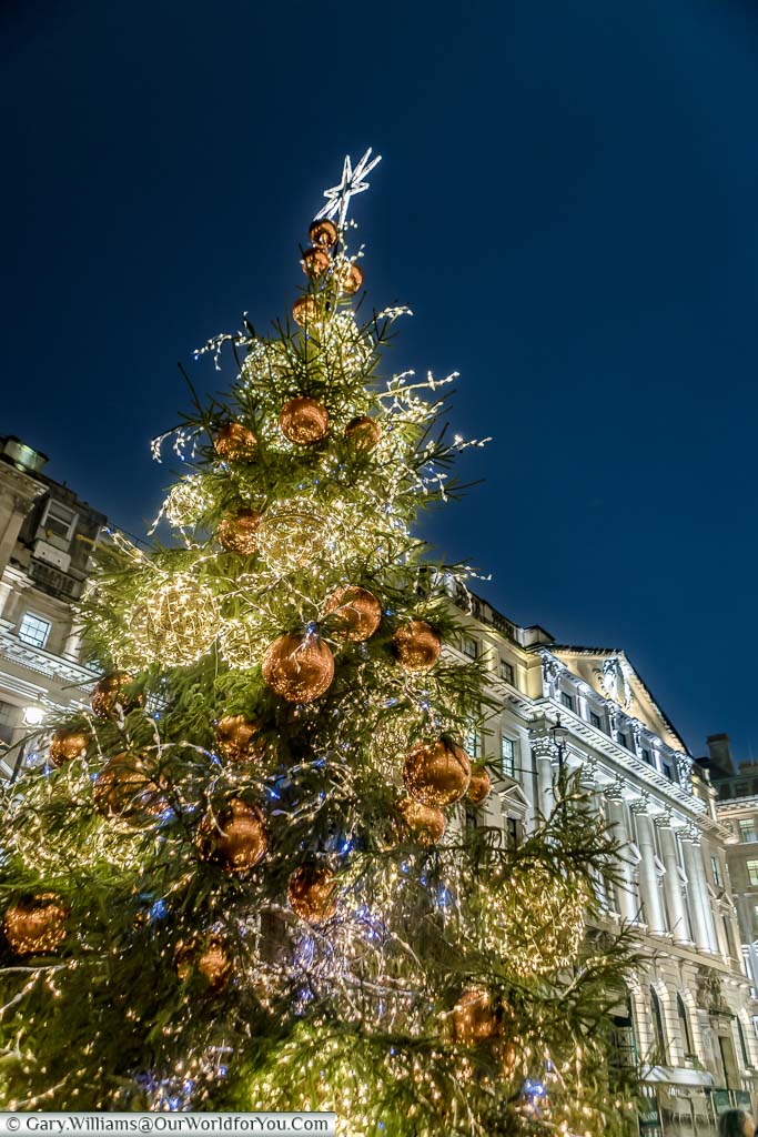 An illuminated traditional Christmas tree decorated with giant red baubles in Central London at Christmas