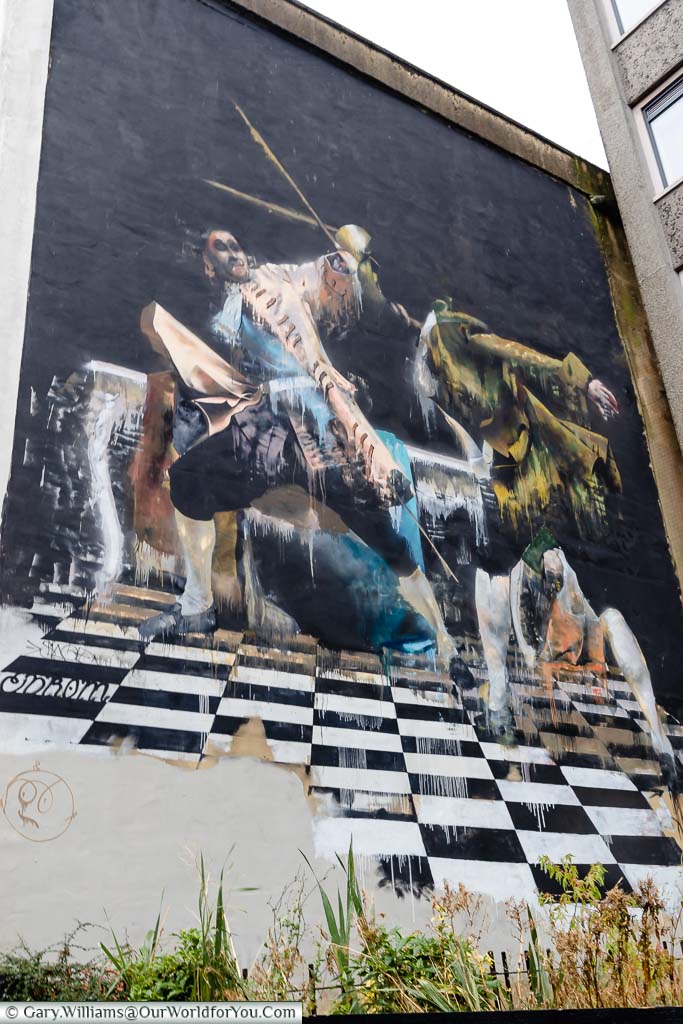 A mural on the side of a building in Bristol of two men duelling on a chessboard.