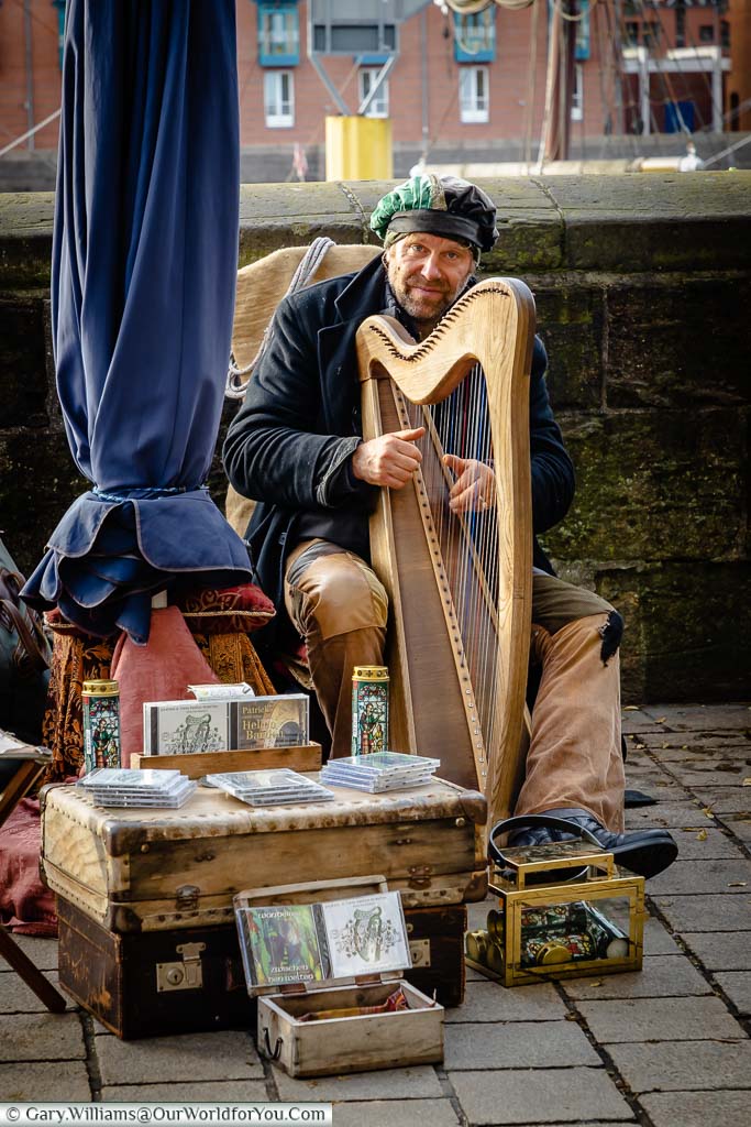 A street musician playing the harp in period costume on the River Christmas Market in Bremen, Germany