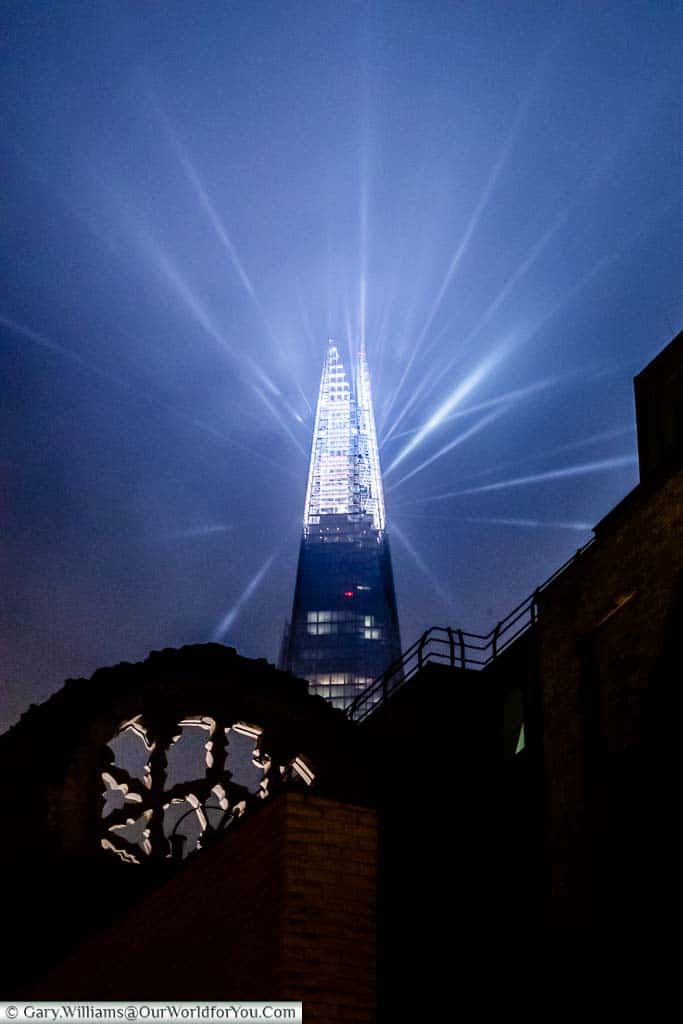 The illuminated tip of the Shard at Christmas from Clink Street with the remains of Winchester Palace in the foreground.