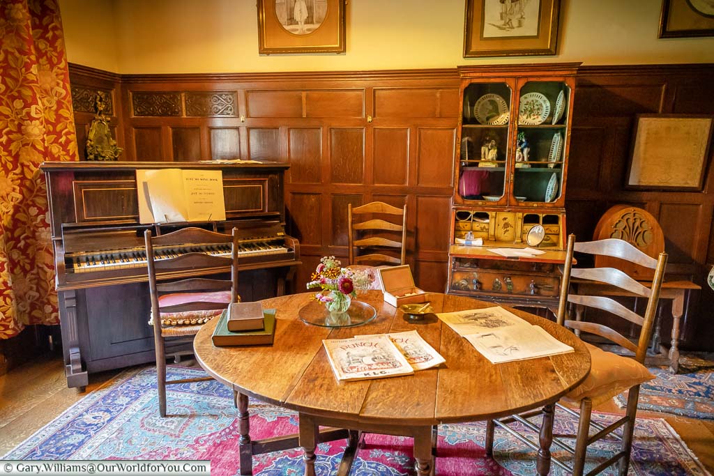 A wooden table takes centre place next to the upright piano in Rudyard Kipling' s music room in Bateman’s.