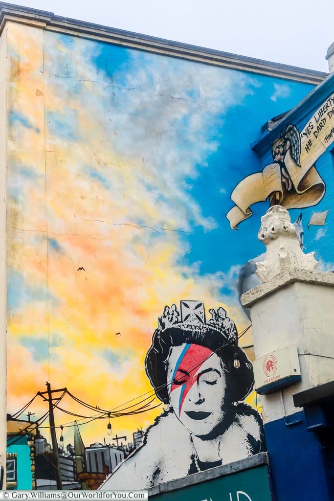 A mural on the side of a building in Bristol depicting a youthful Queen Elizabeth II wearing David Bowie's Ziggy Stardust makeup