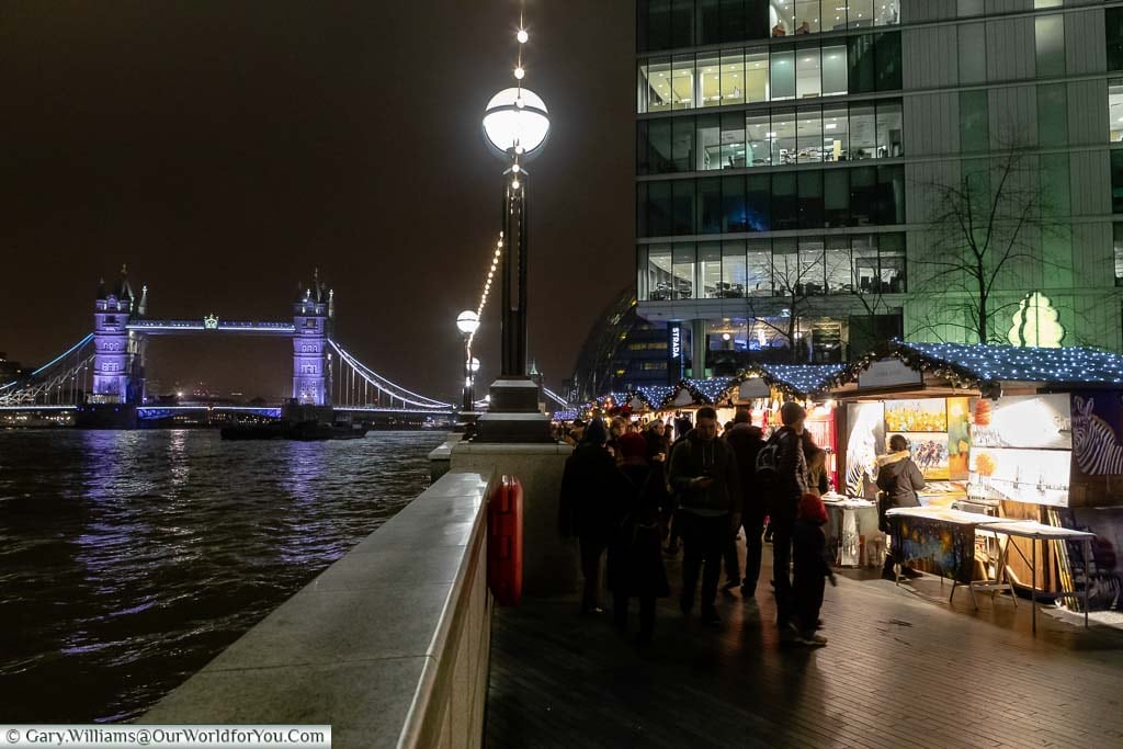 On the south bank of the River Thames, the Christmas by the River market, with the illuminated Tower Bridge in the background.