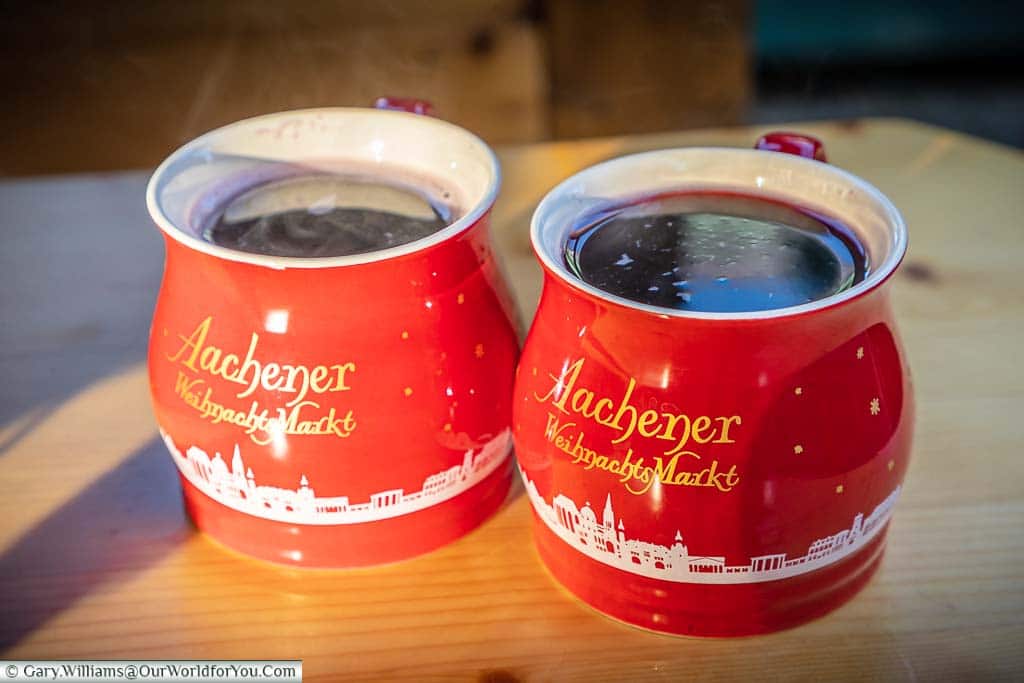 Two beautiful bright red mugs from the Aachener WeihnachtsMarkt filled with steaming Glühwein