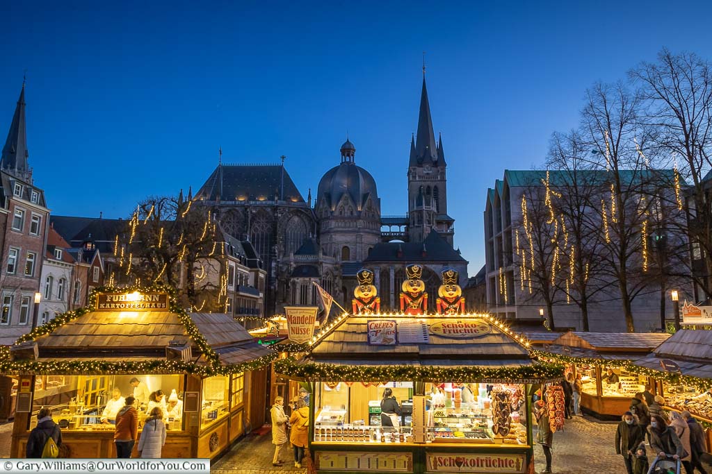 At dusk, stalls lit up in Aachen's Christmas Market in front of the Cathedral.