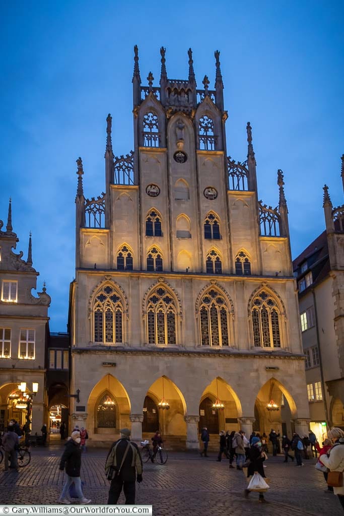 A front view of Münster’s Rathaus at dusk under a blue sky.