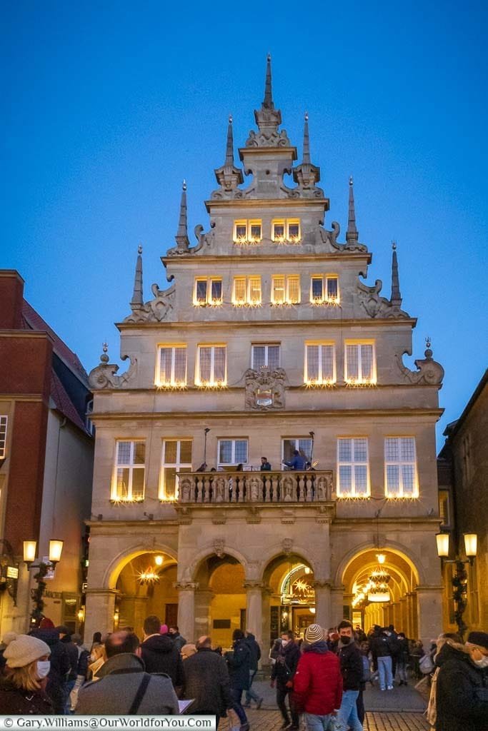 The beautiful facade of the Stadtweinhaus in Münster, with a classical band laying Christmas carols from the first-floor balcony