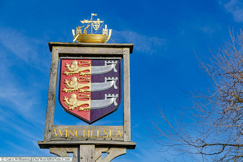 The Winchelsea village sign featuring the coat of arms of the Cinque Ports with a golden galleon on top.