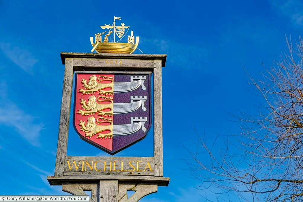 The Winchelsea village sign featuring the coat of arms of the Cinque Ports with a golden galleon on top.