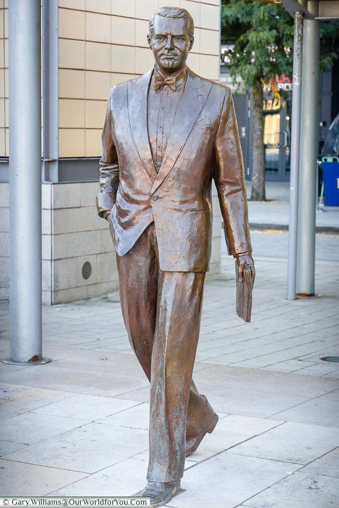 A bronze statue to a sharply dressed Cary Grant in the Millennium Square of Bristol