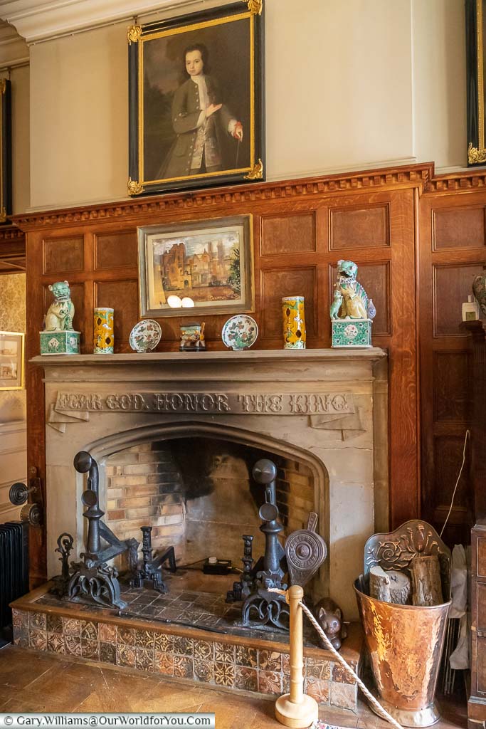 A portrait above the stone fireplace set in wood panelling in the entrance hall at Scotney House