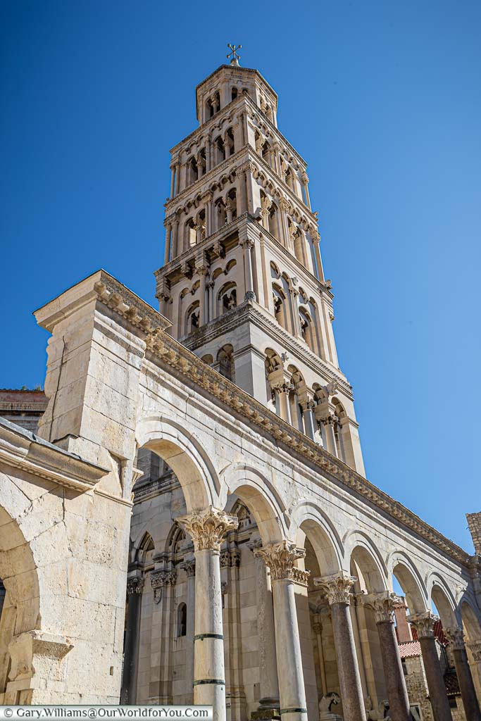 The golden stone tower of Split cathedral against a deep blue sky in Croatia