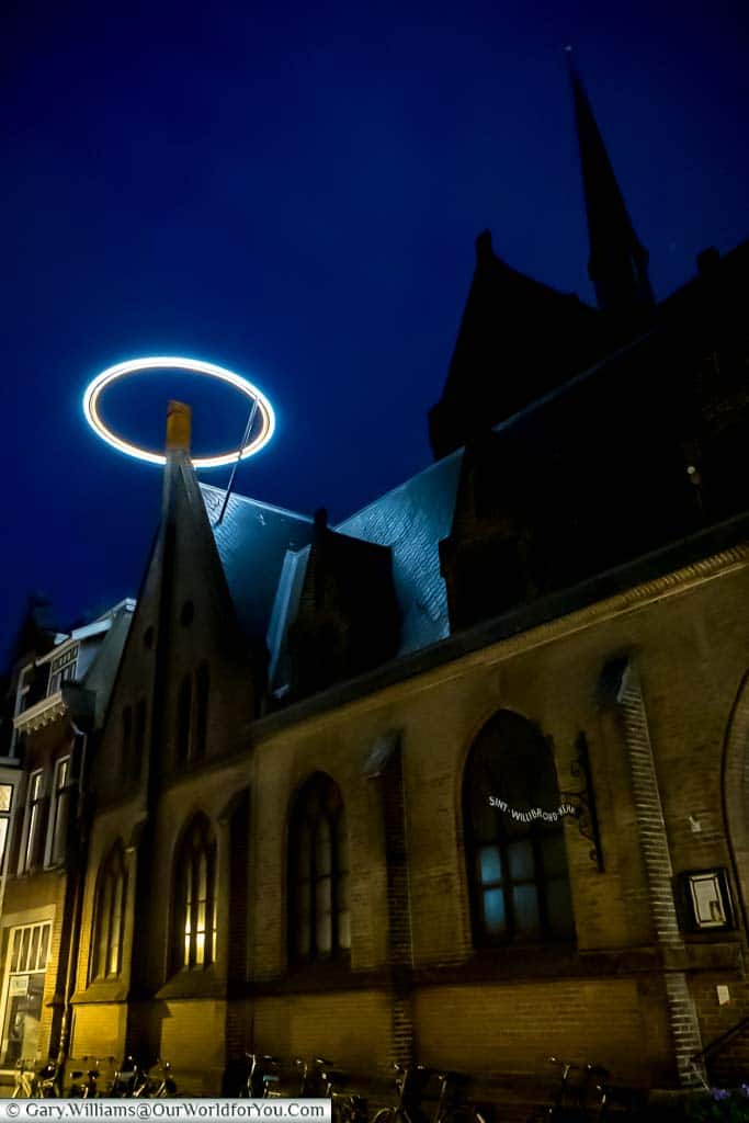 An illuminated saintly ring mounted above a gable as part of the Trajectum Lumen project in Utrecht, Netherlands