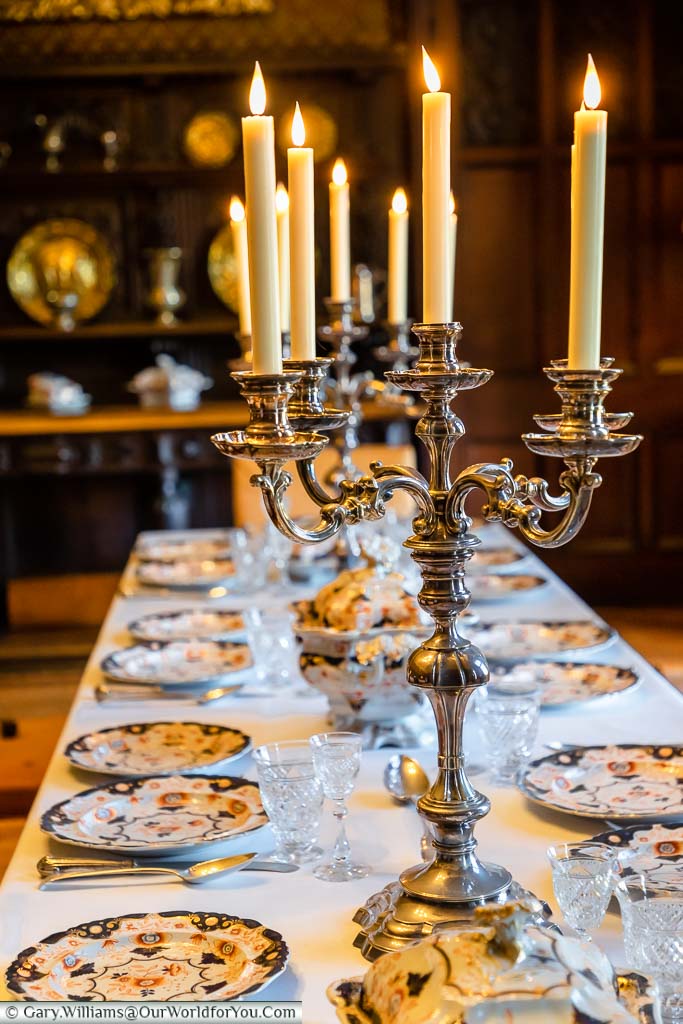 Ornate candlestick holders lined up on the set dining table in the dining room of Scotney House