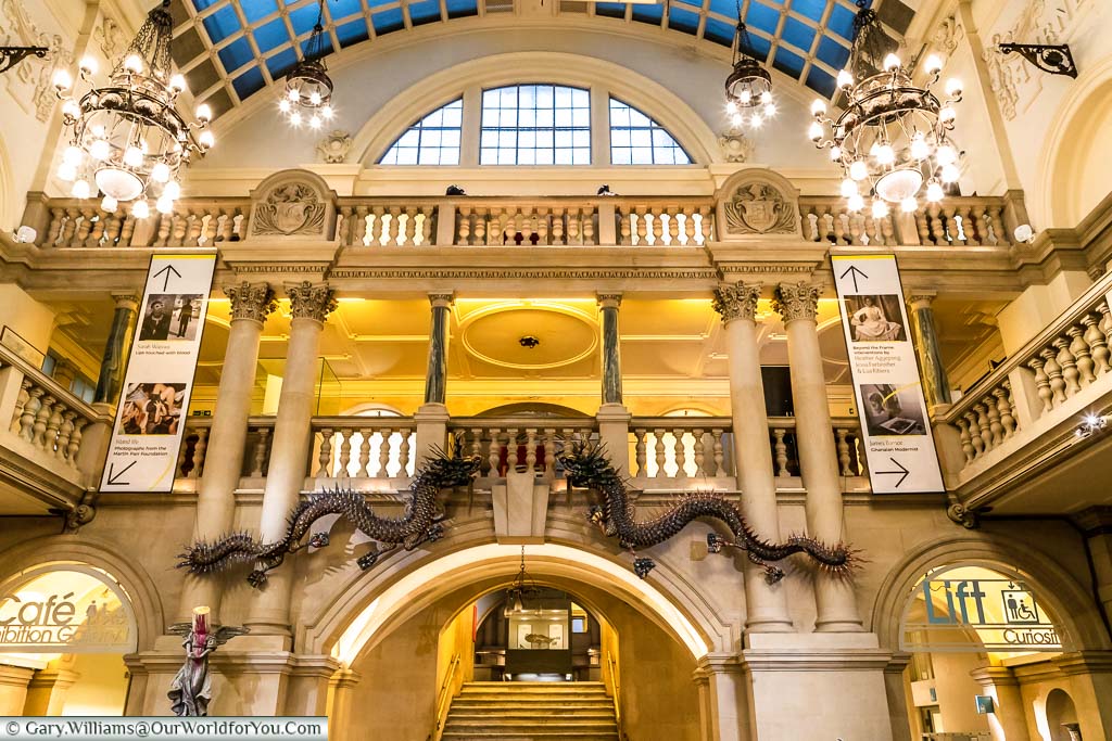 The classically styled entrance hall of Bristol Museum with exquisite chandeliers and Banksy's Paint pot angel at the foot of the stairs