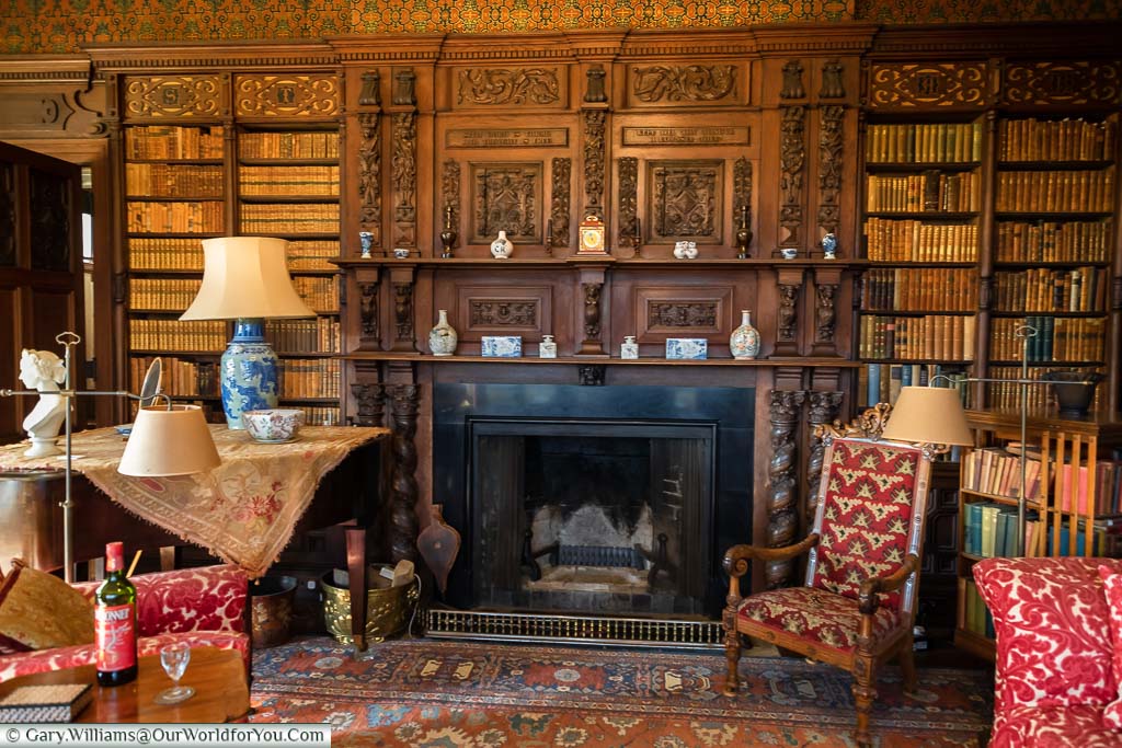 The dark oak bookshelves surrounding the fireplace of the library in Scotney House