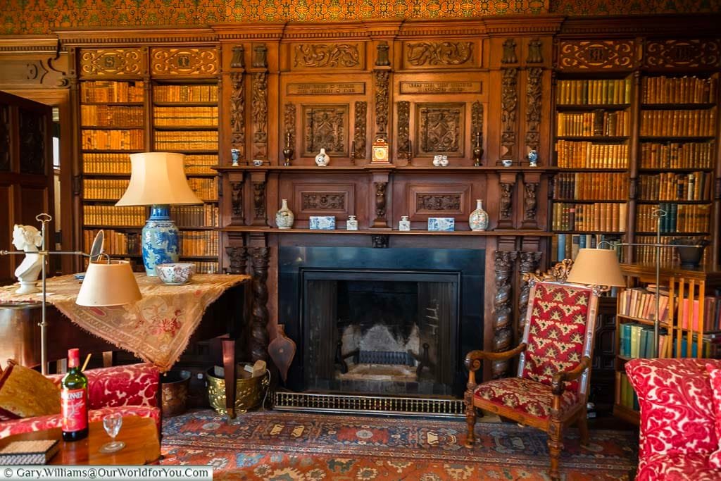 The dark oak bookshelves surrounding the fireplace of the library in Scotney House