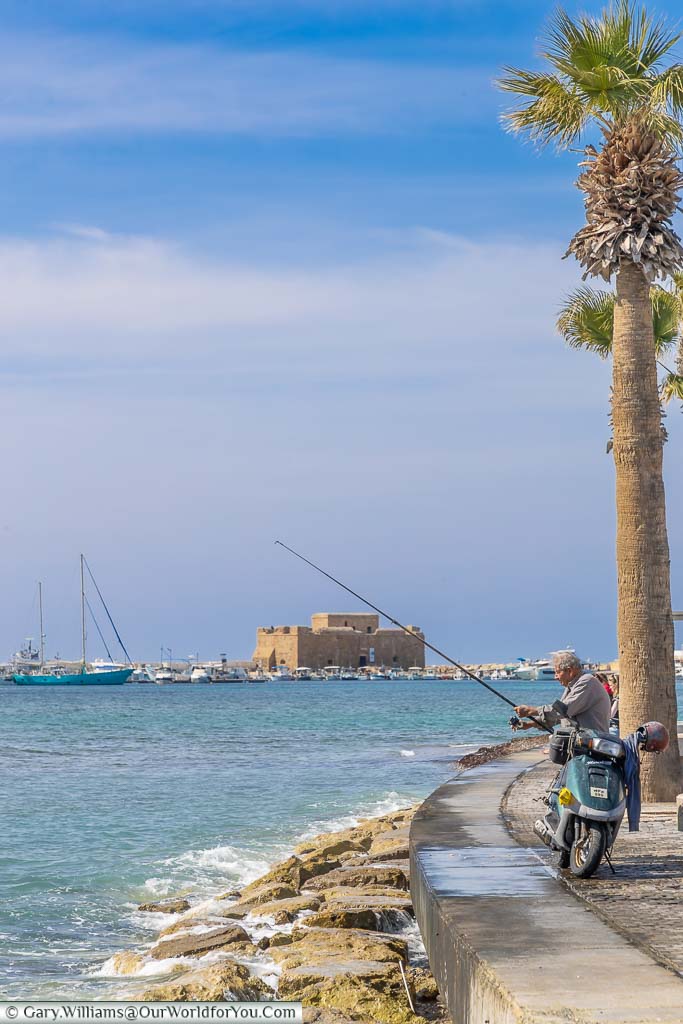 An old man fishing off Paphos harbour with the Castle in the background