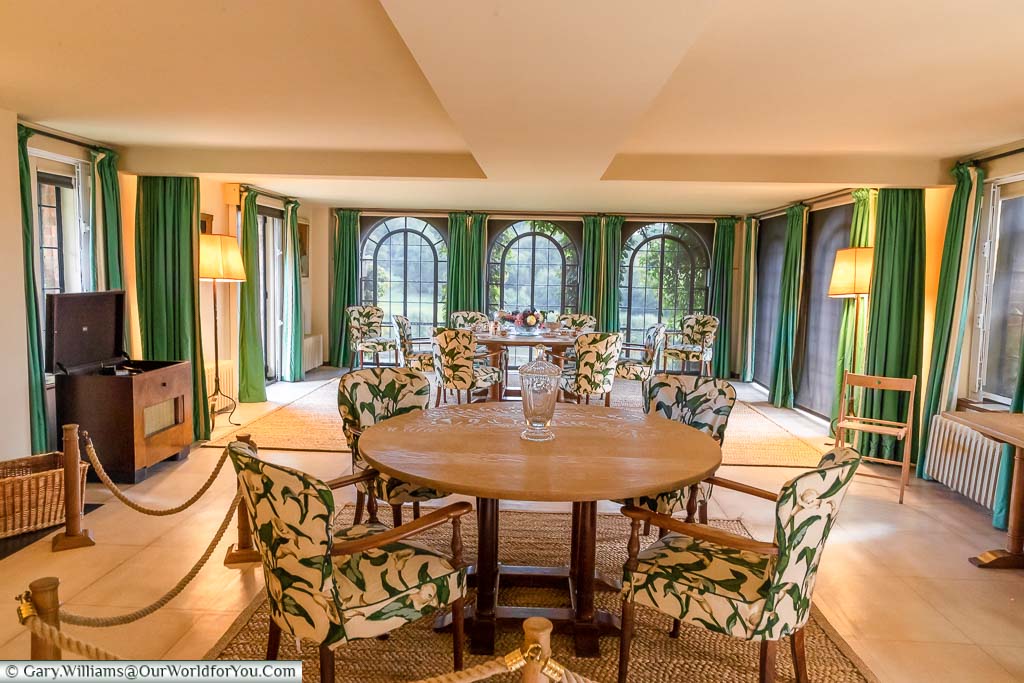 Two small tables with comfortable chairs in Chartwell's Dining Room with its full-length arched windows overlooking the grounds