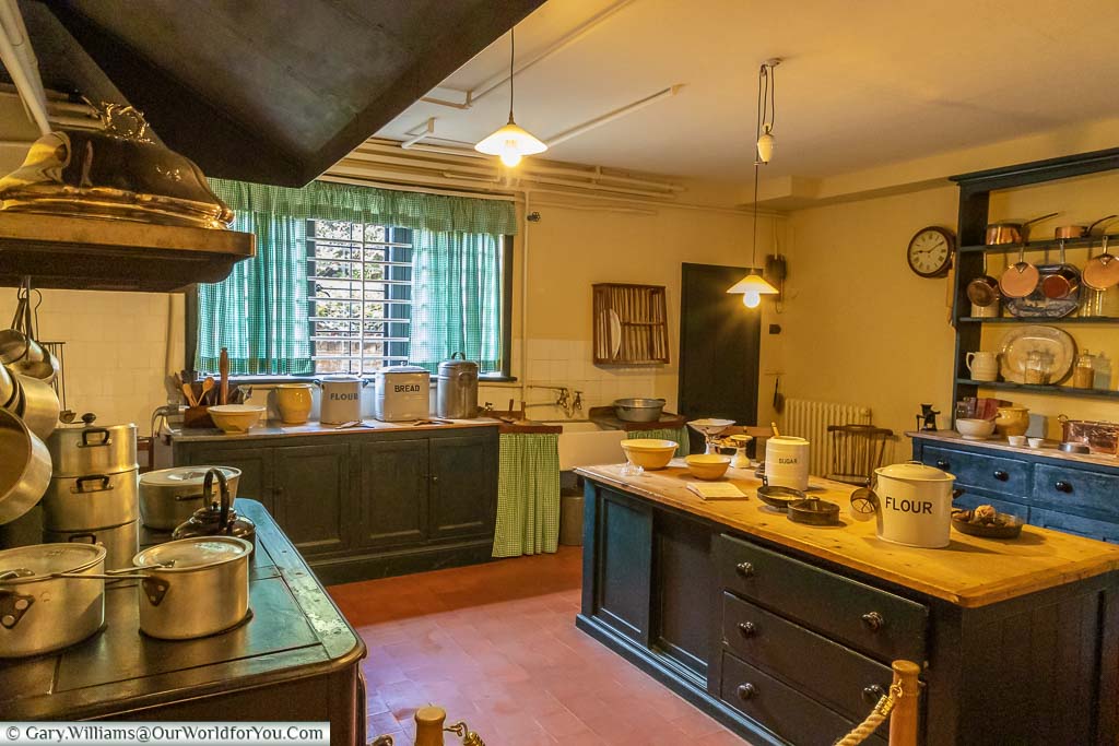 The traditionally equipped mid-20th-century kitchen at Chartwell House, with pots and pans on the Aga cooker, a wooden topped centre console and a kitchen dresser in the background.