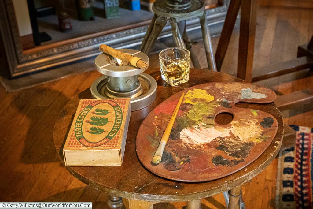 A glass of Whisky, a partially smoked cigar resting in an ashtray, a box of three cocks mints and an artist's paint palette in Sir Winston Churchill's studio in the grounds of Chartwell.