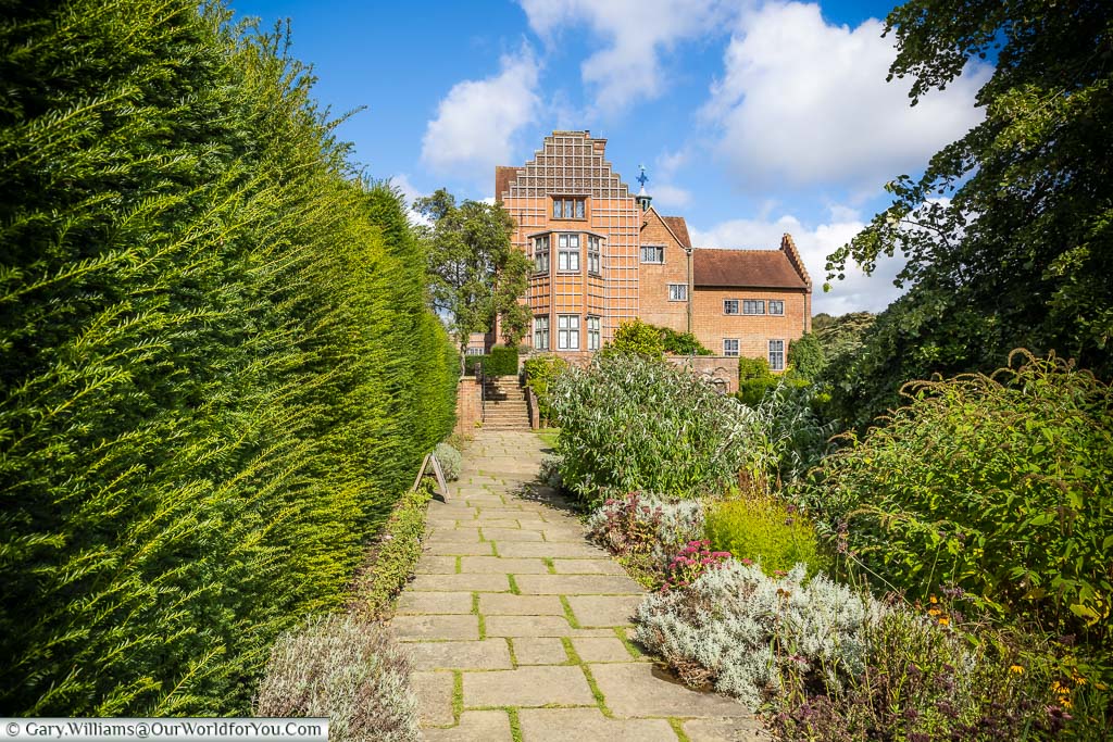 A view along a hedge-lined path to the south-facing red-brick wall of Chartwell House.