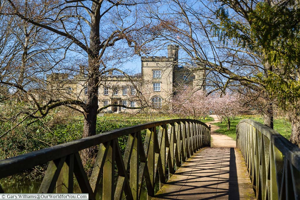 A wooden bridge leading to the 19th Century Chiddingstone Castle on a bright spring day