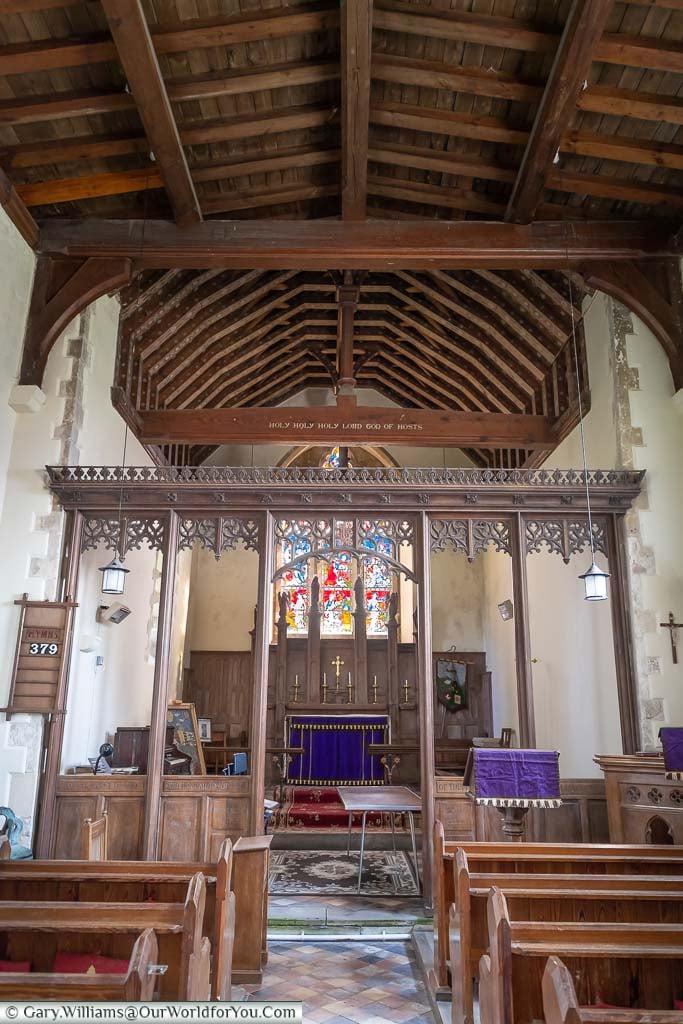 Inside All Saints Church in Burmarsh, with its vaulted wooden roof, and stained glass window above the altar.