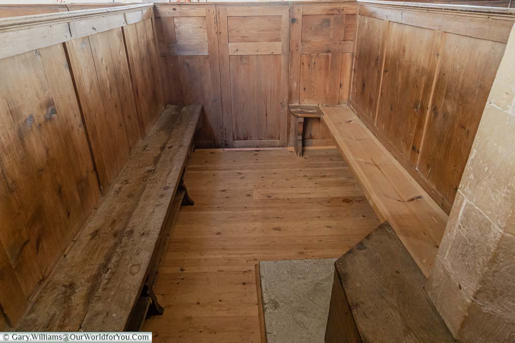 The inside of a wooden box-pew in the Church of St Augustine with the benches facing each other