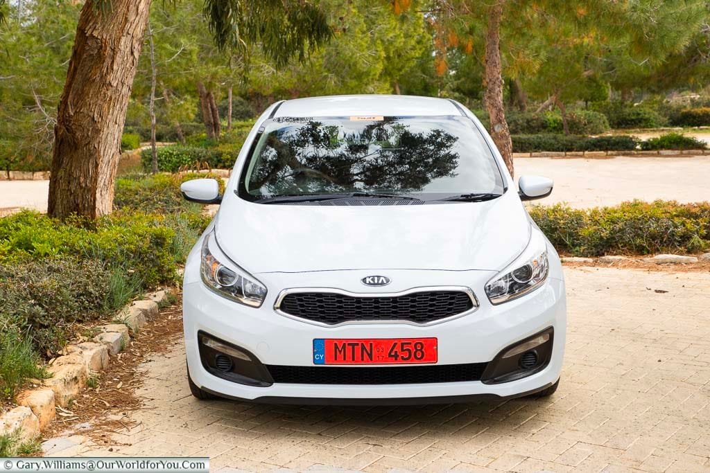 A front-on view of our white Kia Ceed hire car in a parking bay