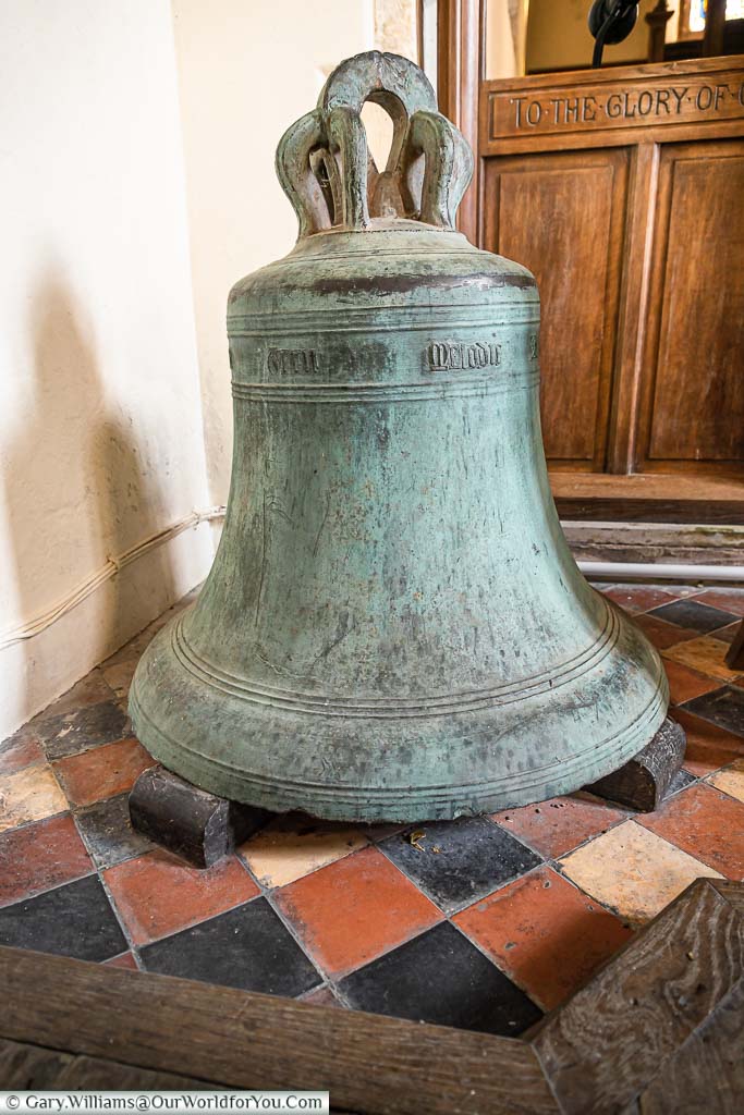 A 15th-century bronze church bell inside All Saints Church, Burmarsh, resting on three wooden blocks.